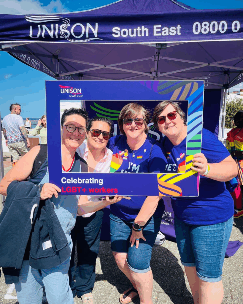 Four people pose in front of the camera at a Pride parade