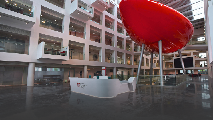 The interior of Solent University with a reception desk and a large red balloon like object known as the Spark