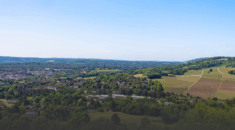 A drone image showing rolling green hills, a bright blue sky and a settlement of villages