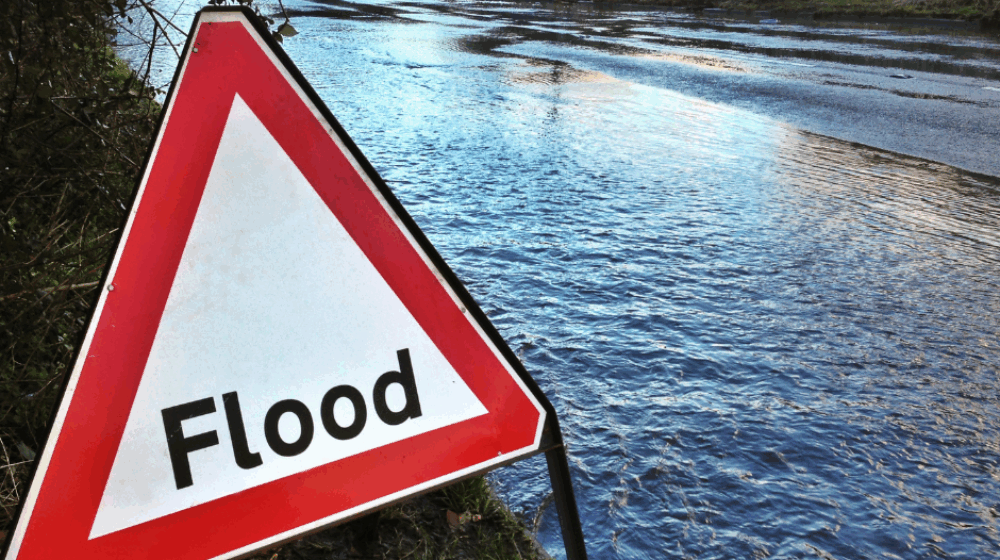 A flooded road with a warning sign