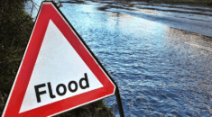 A flooded road with a warning sign