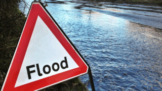 A flooded road with a warning sign