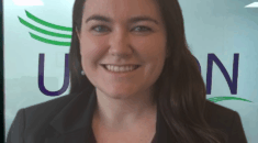 A woman stands in front of the UNISON logo in an office